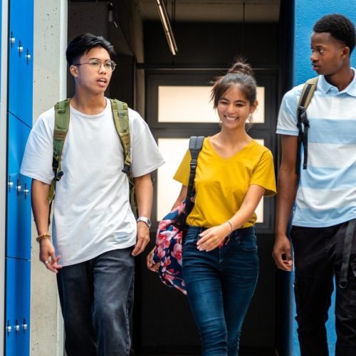 ultiracial teen high school students changing classes walking in school corridor. Back to school.